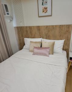 a white bed with a pink pillow on it at SHERISSE' CONDO @ THE LOOP WITH WIFI,CABLE AND HOT & COLD SHOWER, in Cagayan de Oro