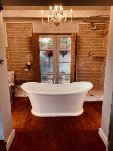 a large white tub in a bathroom with a window at Gorgeous Bruton Chic Lakeside Boat House. in Bruton