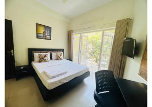 1 dormitorio con 1 cama, 1 silla y 1 ventana en BluO 1BHK Salt Lake - Kitchen, Balcony, Parking ,Terrace, en Calcuta