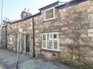 an old stone building with windows on a street at Weaver's Cottage in Porthmadog