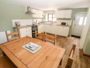 a kitchen and dining room with a wooden table and chairs at Weaver's Cottage in Porthmadog