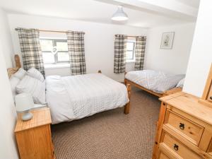une chambre avec deux lits et une commode dans l'établissement Weaver's Cottage, à Porthmadog