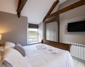 a bedroom with a bed with white sheets and a window at Mino Cottage in Port Isaac