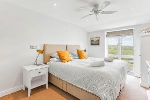 a white bedroom with a bed with orange pillows at 6 Ocean's Edge in Kingsbridge +16 photos