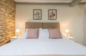 1 dormitorio con 1 cama blanca grande y 2 almohadas en Eastnor, en Moreton-in-Marsh