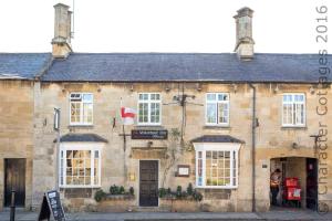 an old stone building with white windows on a street at The Brew House in Chipping Campden