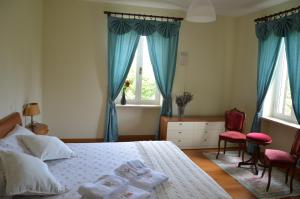 Bed & Bistrò Che Piasì في Calamandrana: غرفة نوم بسرير والستائر الزرقاء وكرسيين