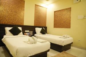 twee bedden in een hotelkamer met handdoeken erop bij Hotel Blue Mystic in Pune
