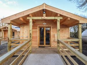 Holzhütte mit Holztür und Veranda in der Unterkunft Buttercup Lodge in Leiston