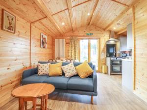 ein Wohnzimmer mit einem blauen Sofa und einem Tisch in der Unterkunft Buttercup Lodge in Leiston