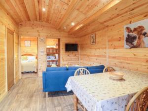 ein Esszimmer mit einem blauen Sofa und einem Tisch in der Unterkunft Buttercup Lodge in Leiston