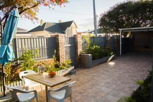 a patio with a table and chairs and an umbrella at Limbila House in Cape Town