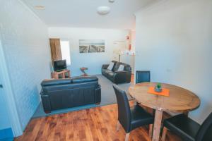 a living room with a table and a couch at Gale Street Motel & Villas in Busselton