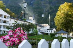 a white fence with pink flowers in front of a building at Fretheim Hotel in Flåm
