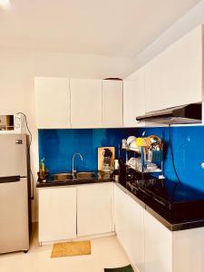 a kitchen with white cabinets and a blue wall at Luxury Cookies Apartment Vung Tau Gold Sea Melody in Vung Tau