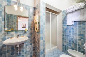 a blue tiled bathroom with a sink and a toilet at Usignoli Apartments - Happy Rentals in Reggello