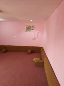 ein Wartezimmer mit einer Couch in einem rosa Zimmer in der Unterkunft Alkithri Apartments for Singls in Muhayil