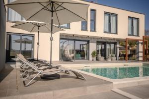 - un ensemble de chaises longues avec un parasol à côté de la piscine dans l'établissement Villa Carlotta, à Vižinada