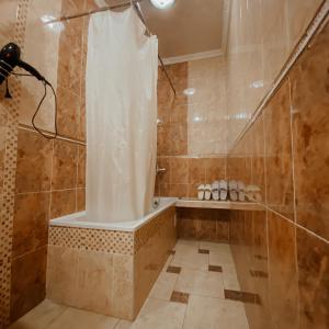 y baño con ducha y cortina de ducha. en Galeon Hotel en Bishkek
