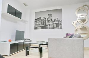 ein Wohnzimmer mit einer Couch, einem Tisch und einem Fernseher in der Unterkunft Apartamento San Sebastián in Conil de la Frontera