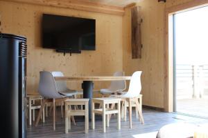 a dining room with a table and chairs and a tv at Chalet Gîte Magali de 2 à 12 pers in Le Noyer