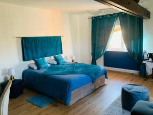 Manoir de la Gravette Maison d'Hôtes في مونتوبان: غرفة نوم بسرير وملاءات زرقاء ونافذة