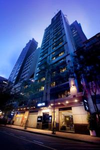 a tall building on a city street at night at Xi Hotel in Hong Kong