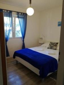Schlafzimmer mit einem Bett mit blauer Bettwäsche und einem Fenster in der Unterkunft Apartment Gana - 50m from the sea in Maslinica