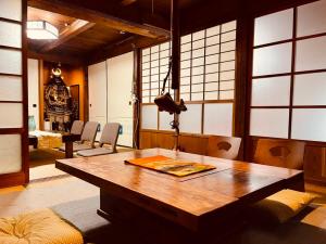 Habitación con mesa de madera, sillas y ventanas. en 皆様お宿　川風 en Hiki