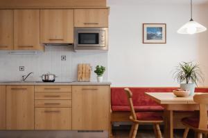 eine Küche mit Holzschränken und einer roten Couch in der Unterkunft Ciasa Willy App Lavarella in Stern
