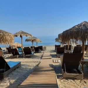 a beach with chairs and straw umbrellas and the ocean at Cozy Home (close to the beach) in Nea Kydonia
