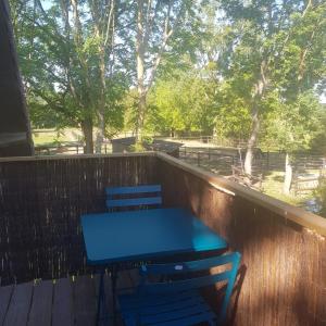 a table and chairs on a deck with a fence at Les gîtes équestre de ninon in Moult