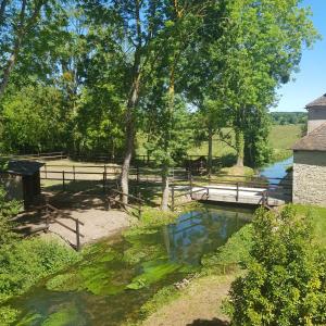 a pond in a field with a bridge and trees at Les gîtes équestre de ninon in Moult
