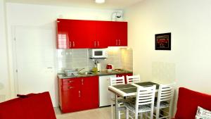 una cucina con armadi rossi e un tavolo con sedie di Studio La Casa a Soko Banja