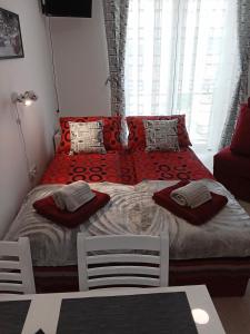 um quarto com uma cama com lençóis e almofadas vermelhas em Studio La Casa em Sokobanja