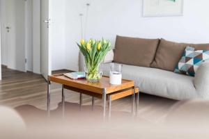 een woonkamer met een bank en een tafel met bloemen erop bij Windrose in Norderney