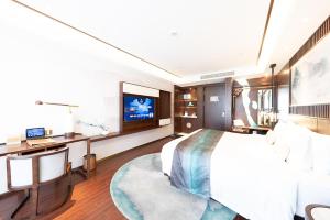 um quarto de hotel com uma cama grande e uma televisão em New Century Hotel Qianchao Hangzhou em Hangzhou