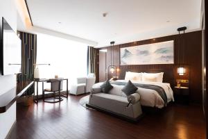 um quarto com uma cama, um sofá e uma secretária em New Century Hotel Qianchao Hangzhou em Hangzhou
