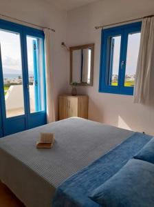 a bedroom with a large bed with blue windows at Glyfada House in Kastraki Naxou