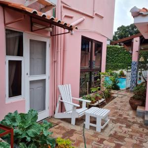 a pink house with a chair and a bench at Casa Quimera in Maputo