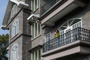 kobieta stojąca na balkonie budynku w obiekcie StayVista at The Mansion w mieście Kasauli