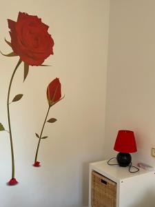 una rosa roja en una pared con una lámpara roja en Apartamento Beatriz, en Cuenca