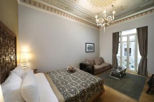a bedroom with a bed and a couch and a chandelier at The Story Hotel Pera in Istanbul