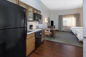 a kitchen with a refrigerator and a bedroom with a bed at Candlewood Suites-West Springfield by IHG in West Springfield
