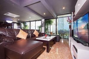 - un salon avec un canapé en cuir et une télévision à écran plat dans l'établissement Exotica Pool Villa Encore, à Pattaya (sud)