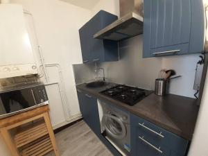 cocina con armarios azules y lavadora en Beau T1 2 personnes BERGSON, en Saint-Étienne