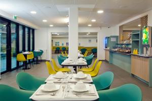 a dining room with tables and yellow chairs at Séjours & Affaires Paris Bagnolet in Bagnolet
