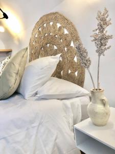 a bed with white pillows and a vase on a table at Casa Jaraíz - Centre town in Caravaca de la Cruz
