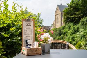 a table with a sign and a vase of flowers on it at Jeanneke Bosch in Schin op Geul