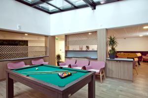 a pool table in a room with pink chairs at Séjours & Affaires Paris Bagnolet in Bagnolet